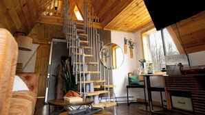 Un interior de madera con una escalera de caracol, un sofá, una mesa de centro y un escritorio con un ordenador.