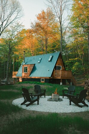 Une cabane dotée d’un toit en pente, d’une façade en bois et d’une terrasse avec des sièges d’extérieur.