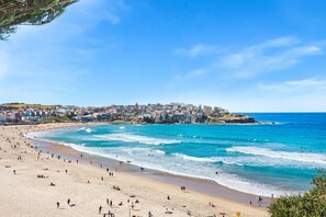 A beach with people, a clear sky, and buildings in the background. - Bondi Bliss Lamrock - 1 minute to beach + Parking (Bondi Beach)