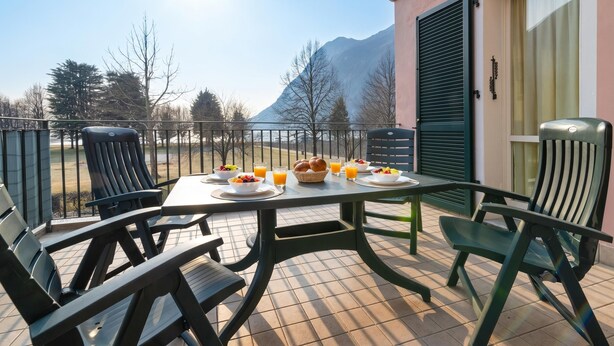 A terrace with a table set for breakfast, chairs, and a view of mountains.