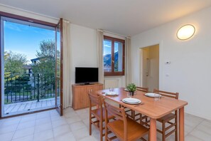 A dining area with a table, chairs, a television, and a view of the outdoors. - Porto Letizia Verdi 5, Porlezza, Italy (Porlezza)