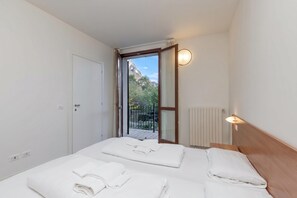 Una camera d'albergo con due letti, vista sull'esterno, un termosifone e una porta.