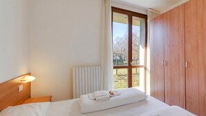 A hotel room with a bed, a window with curtains, a radiator, and a wardrobe. - Porto Letizia Verdi 1, Porlezza, Italy (Porlezza)