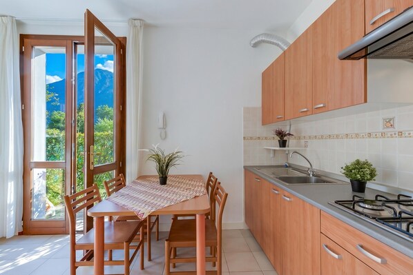 Une cuisine avec des meubles de rangement en bois, une cuisinière à gaz, un évier et une table à manger avec des chaises.