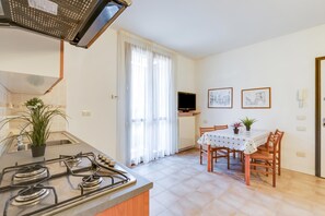 A kitchen with a stove, sink, and dining area with chairs and a table.