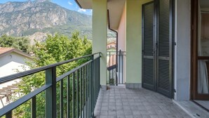 A balcony with a view of mountains, a tiled floor, and a green railing.