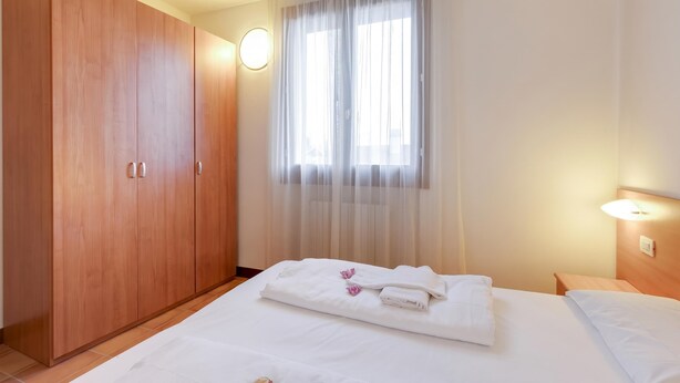 A hotel room with a bed, a wardrobe, a window with curtains, and a bedside lamp. - Porto Letizia Chopin 9, Porlezza, Italy (Porlezza)