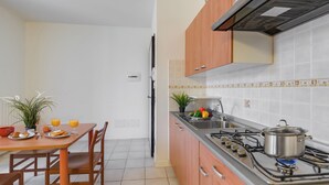 Cozinha com armários de madeira, fogão a gás e área de jantar com mesa posta para o café da manhã.