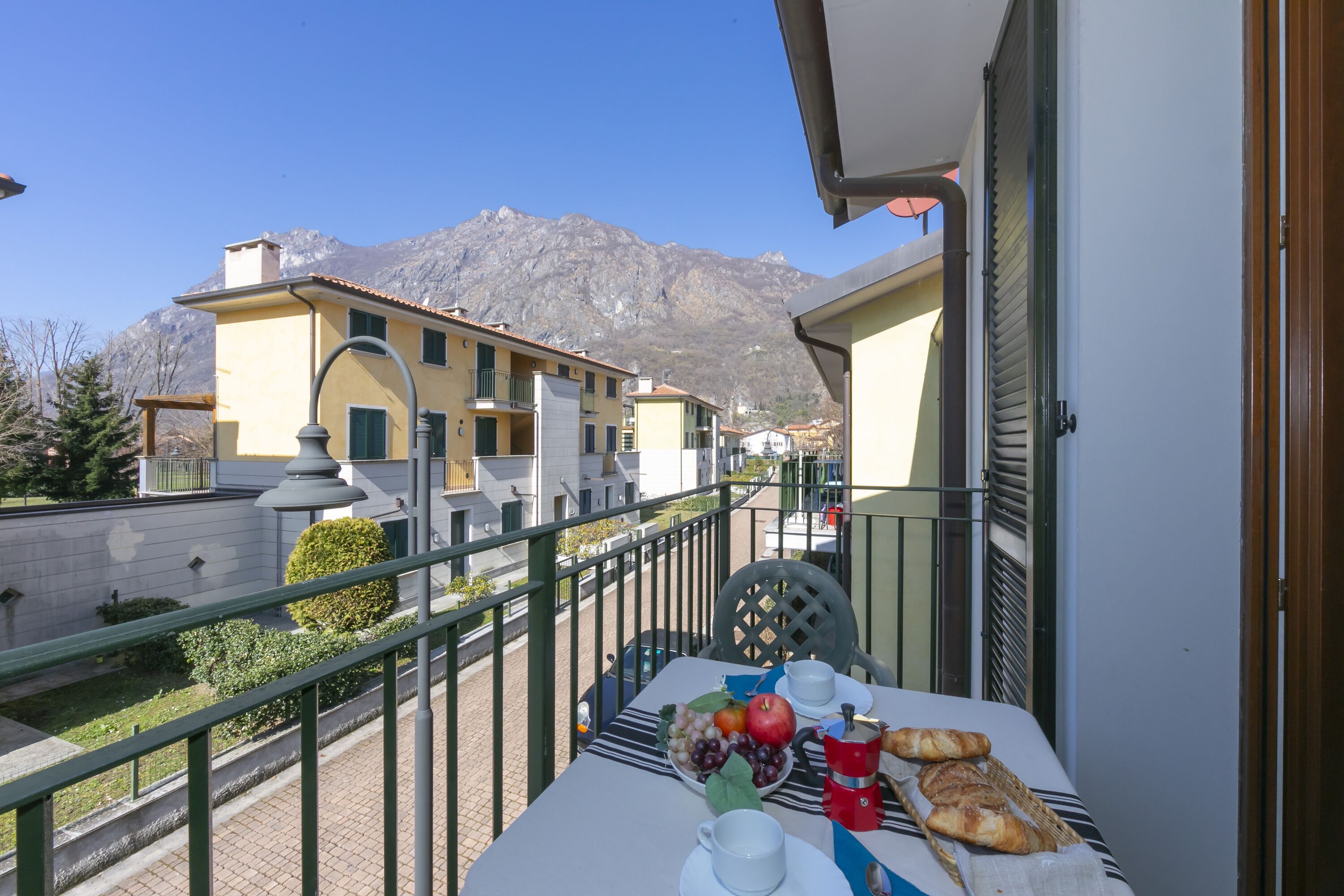 A balcony with a table set for breakfast, overlooking a mountainous landscape.