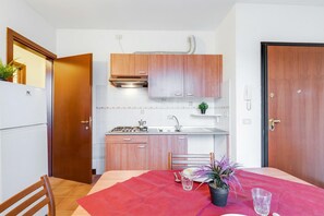 Une cuisine de taille réduite, avec des meubles de rangement en bois, une cuisinière à gaz et un évier.