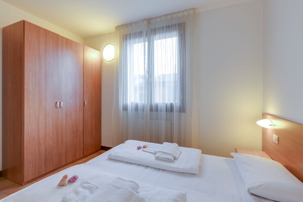 A hotel room with a bed, a wardrobe, and a window with sheer curtains. - Porto Letizia Chopin 5, Porlezza, Italy (Porlezza)