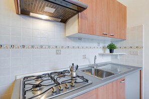 A kitchen with a gas stove, stainless steel sink, and wooden cabinets. - Porto Letizia Chopin 5, Porlezza, Italy (Porlezza)