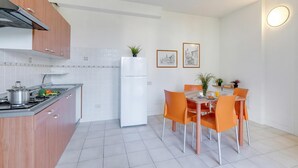 Una cuina moderna amb fogó, nevera i taula de dinar amb cadires.