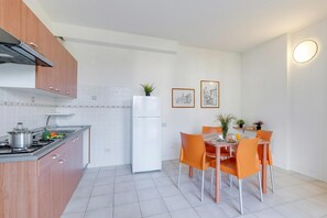 Una cocina moderna con estufa, refrigerador y mesa de comedor con sillas.