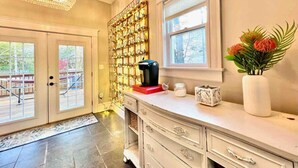 Une cuisine équipée d’une machine à café, d’un vase avec des fleurs et d’un mur décoratif.