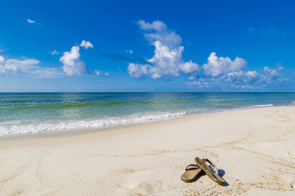 A beach with a pair of flip-flops on the sand.