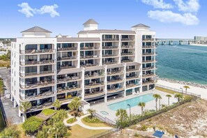 A multi-story hotel with balconies, a pool, and a view of the ocean.