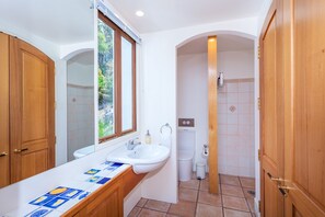 A compact bathroom with a sink, toilet, and shower.