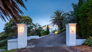 A gated entrance with a sign reading "NAXOS" leading to a building with multiple balconies. - Santorini style, luxury apartment, stunning views! (Bowentown)