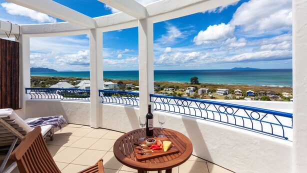 A balcony with a table set for two, a bottle of wine, and a cheese board. - Santorini style, luxury apartment, stunning views! (Bowentown)