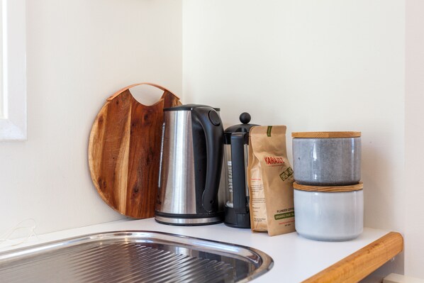 A kitchen counter with a coffee maker, a kettle, a bag of coffee, and a container.