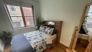 A bedroom with a bed, a wooden headboard, a large window, and a mirror. - Charming 1 Bedroom Industrial Loft w/ Dedicated Parking (Portland)