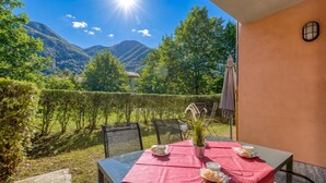 Une table dressée à l’extérieur, avec vue sur les montagnes, une plante en pot et un ciel ensoleillé.