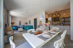 A modern living room with a dining area, featuring a long table set for a meal, a sofa, and a TV in the background. - Porto Letizia Primula 1, Porlezza, Italy (Porlezza)