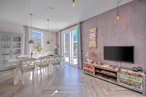 Un soggiorno moderno con zona pranzo, ampie finestre e televisore a schermo piatto.