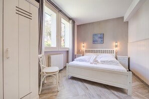 Et soveværelse med seng, stol, radiator, et vindue med gardiner, og en væg med et motiverende citat.