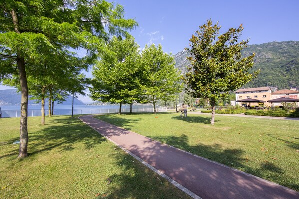 A park with a paved path, trees, and a building in the background.