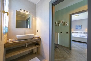 A modern bathroom with a large sink, mirror, and a "HOME" sign on the wall.