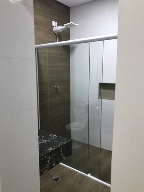 A modern bathroom with a glass-enclosed shower, a marble sink, and a wooden accent wall. - Hotel Novo Apulia (São Paulo)