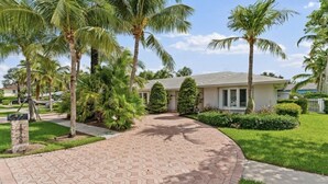 A house with a paved driveway, palm trees, and a well-maintained lawn. - Jupiter waterfront - dock and new  jacuzzi spa , 3 b 2 b fits 30 “ boat   (Jupiter)