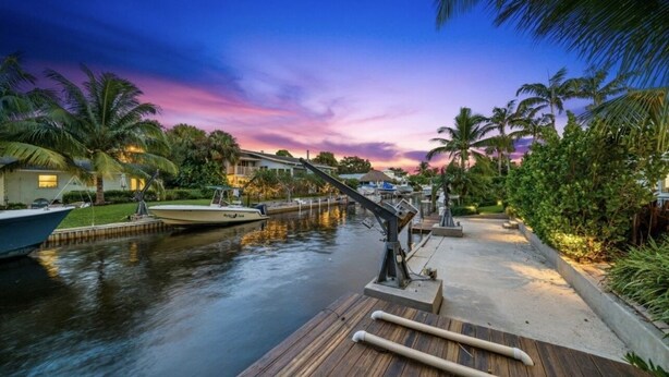 A waterfront property with a dock, boats, and a sunset view. - Jupiter waterfront - dock and new  jacuzzi spa , 3 b 2 b fits 30 “ boat   (Jupiter)