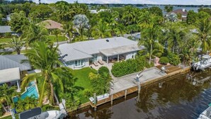 A house with a pool, surrounded by palm trees and a dock extending into a body of water. - Jupiter waterfront - dock and new  jacuzzi spa , 3 b 2 b fits 30 “ boat   (Jupiter)