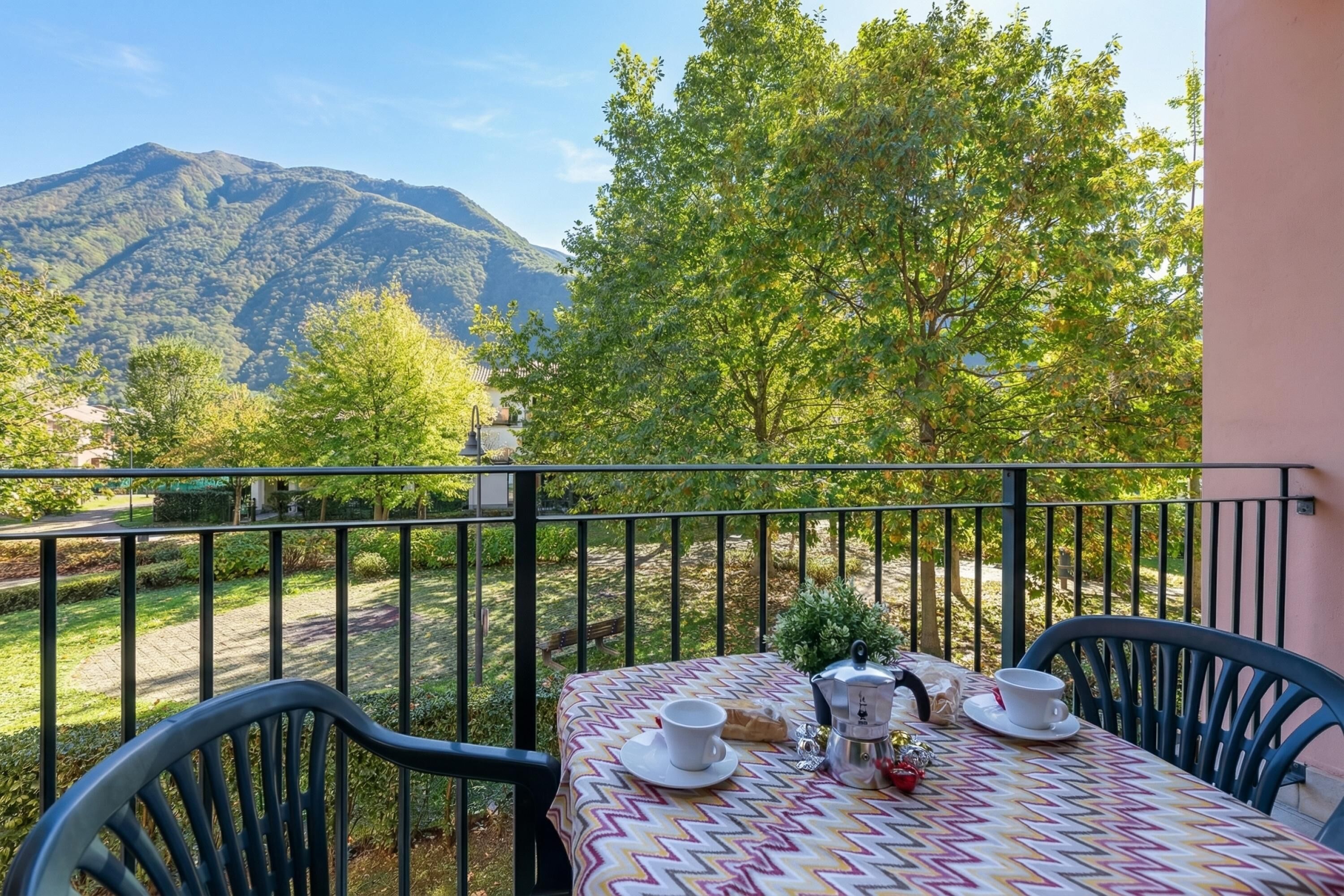 A balcony with a table set for two, overlooking a mountainous landscape.
