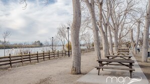 Un parque con mesas de picnic y una cerca de madera a lo largo de un sendero junto al lago.