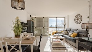 Una sala de estar moderna con comedor, ventanas grandes y un sofá acogedor.