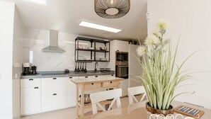 Una cocina moderna con armarios blancos, una mesa de comedor de madera y una planta en maceta.