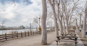 Een park met picknicktafels en een houten hek langs een wandelpad aan het meer.