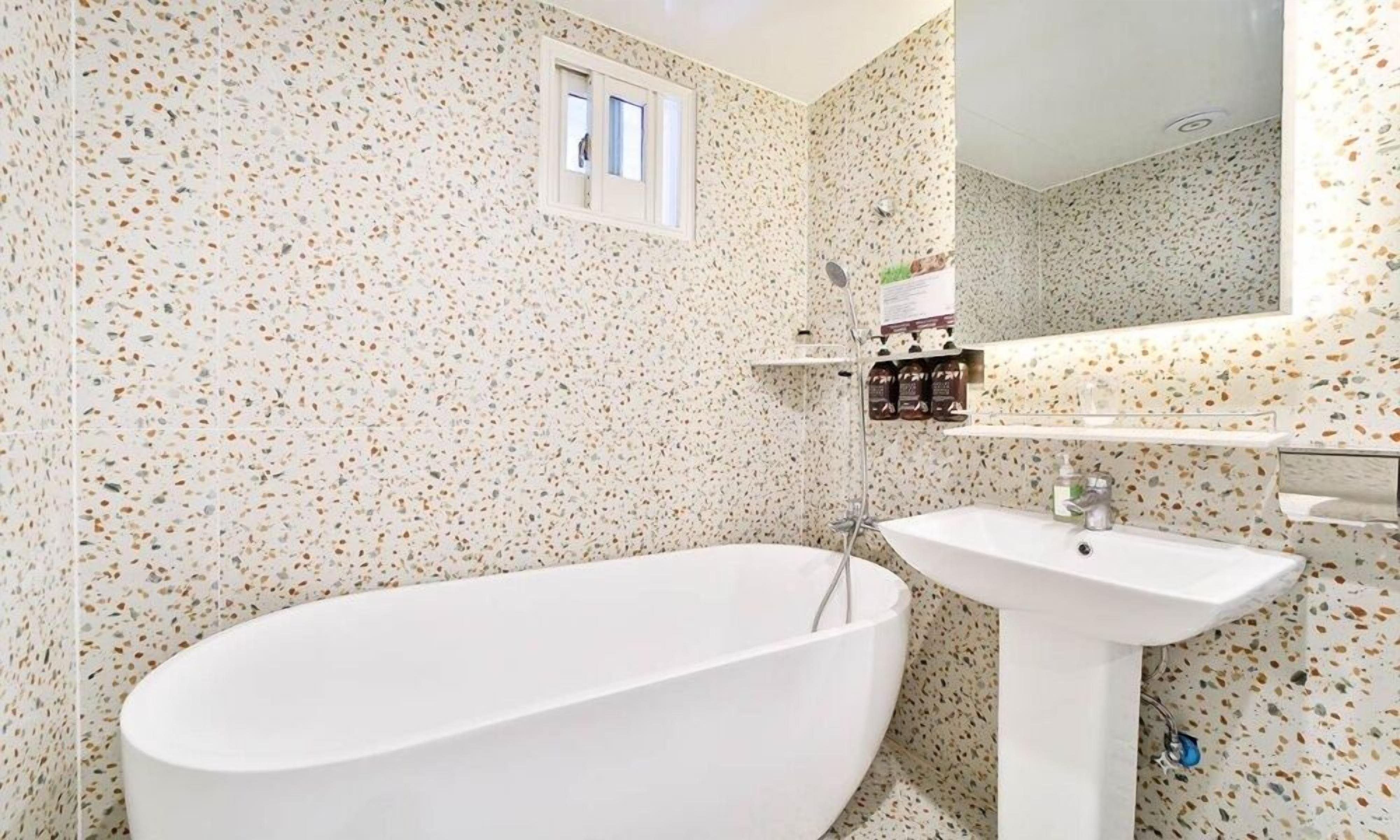 Un baño con una bañera independiente, un lavamanos pedestal y un espejo sobre el lavamanos.