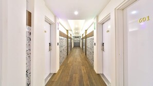 Een hotelhal met marmeren wanden, houten vloer en deuren met de nummers 601 en 602.