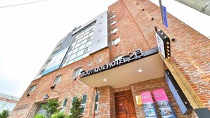 Een boetiekhotel met een gevel van baksteen, grote ramen en een bord dat een feestelijke opening aankondigt.