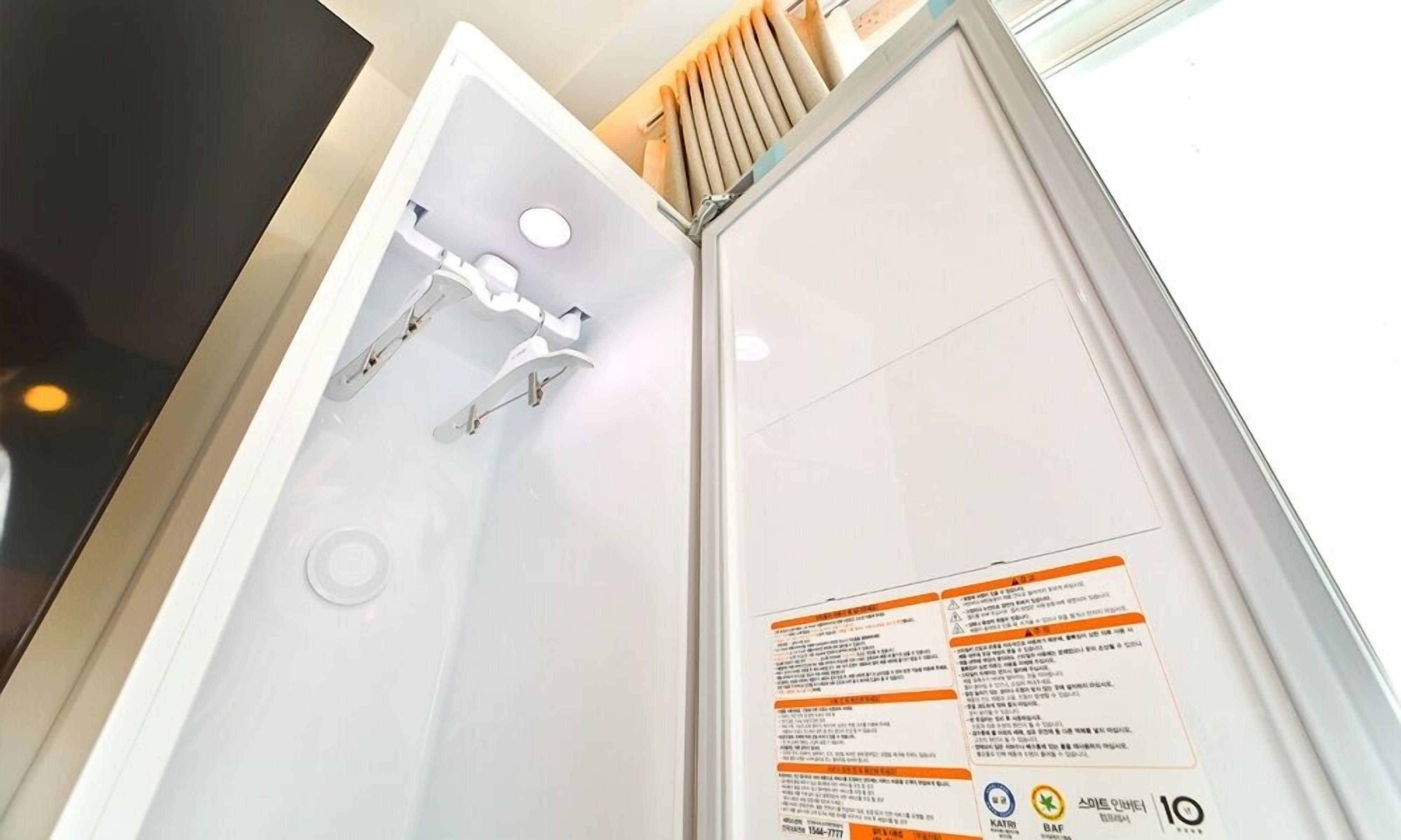 A modern bathroom with a glass shower enclosure, a visible showerhead, and a safety instruction panel.