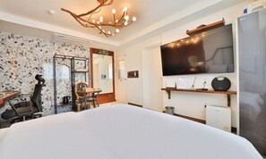 A hotel room with a large bed, a TV, a desk with a chair, a coffee machine, and a unique chandelier. - Hotel February Tongyeong Jukrim (Tongyeong)