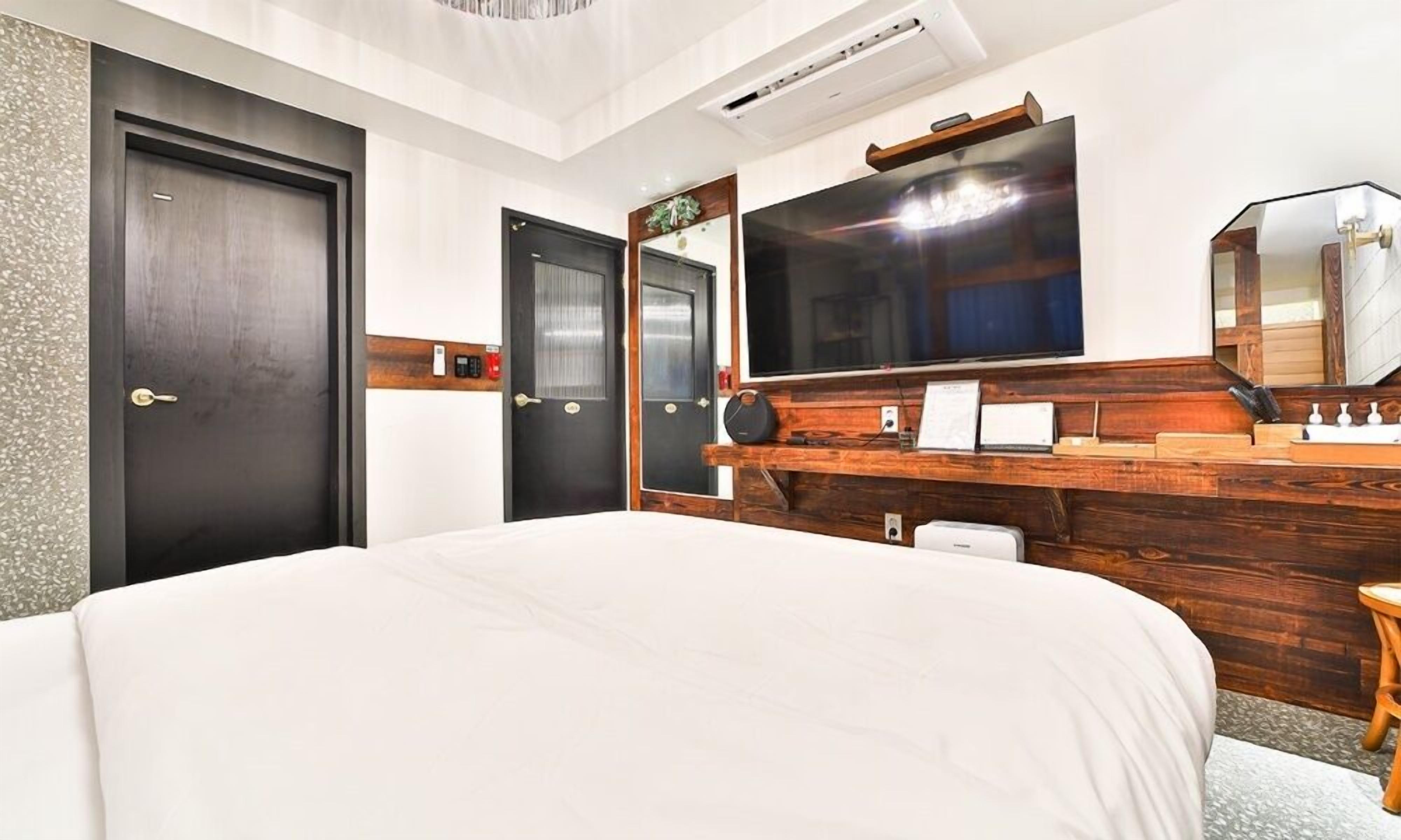 A hotel room with a large bed, a wooden dresser, a flat-screen TV, and a mirror.