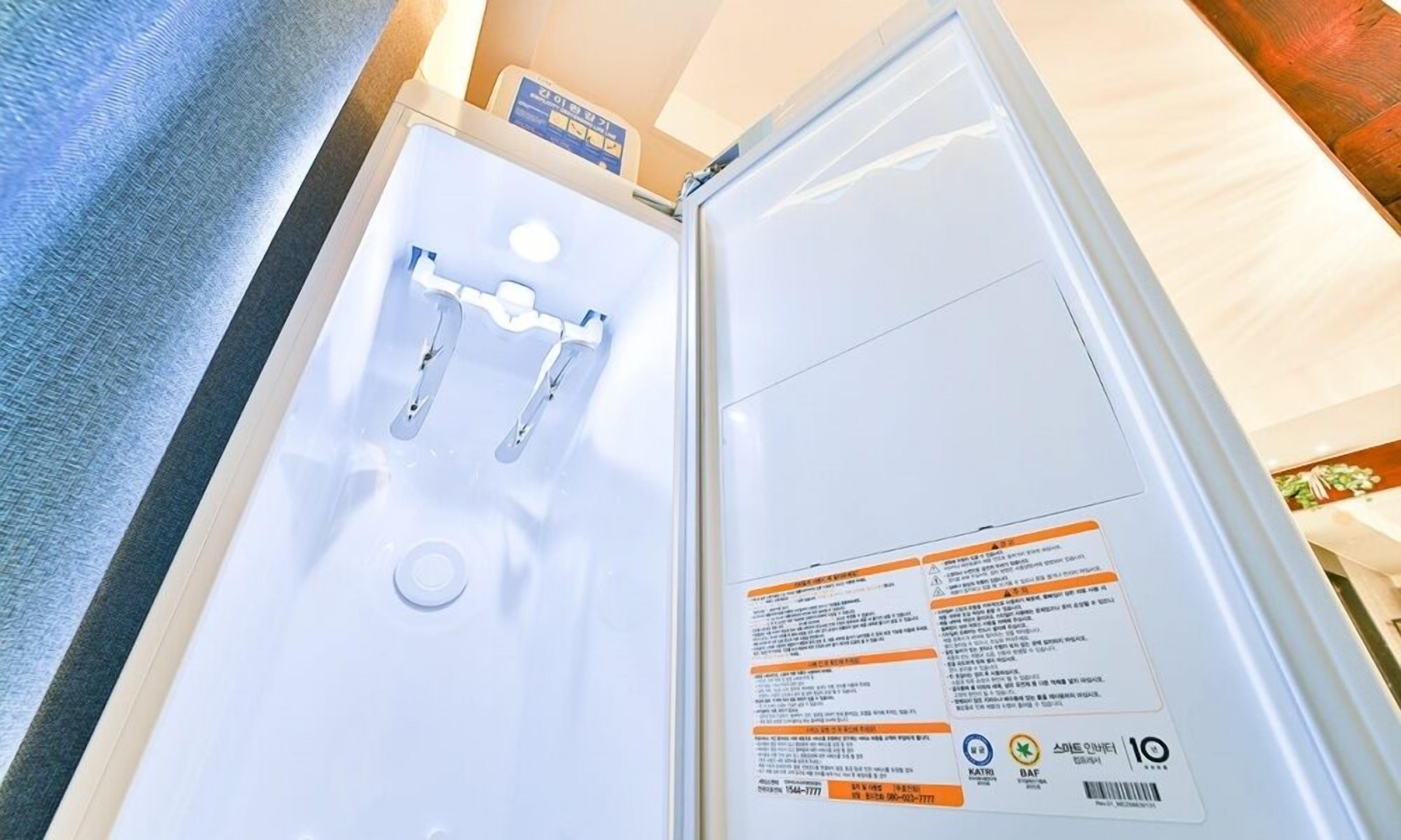 A bathroom with a white sink, a mirror, and a towel rack. There is a sign with text and symbols on the wall.