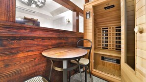 Een houten interieur met een ronde tafel en stoel, een sauna met houten panelen, en een hanglamp.