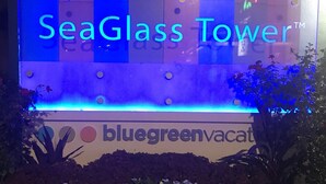 A sign for SeaGlass Tower with a blue neon sign and a banner for BlueGreen Vacation. - One Bedroom Condo, Myrtle Beach 3317100 (Myrtle Beach)